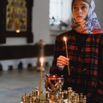 Teenager holding a candle in an Orthodox church, exemplifying spirituality and introspection.