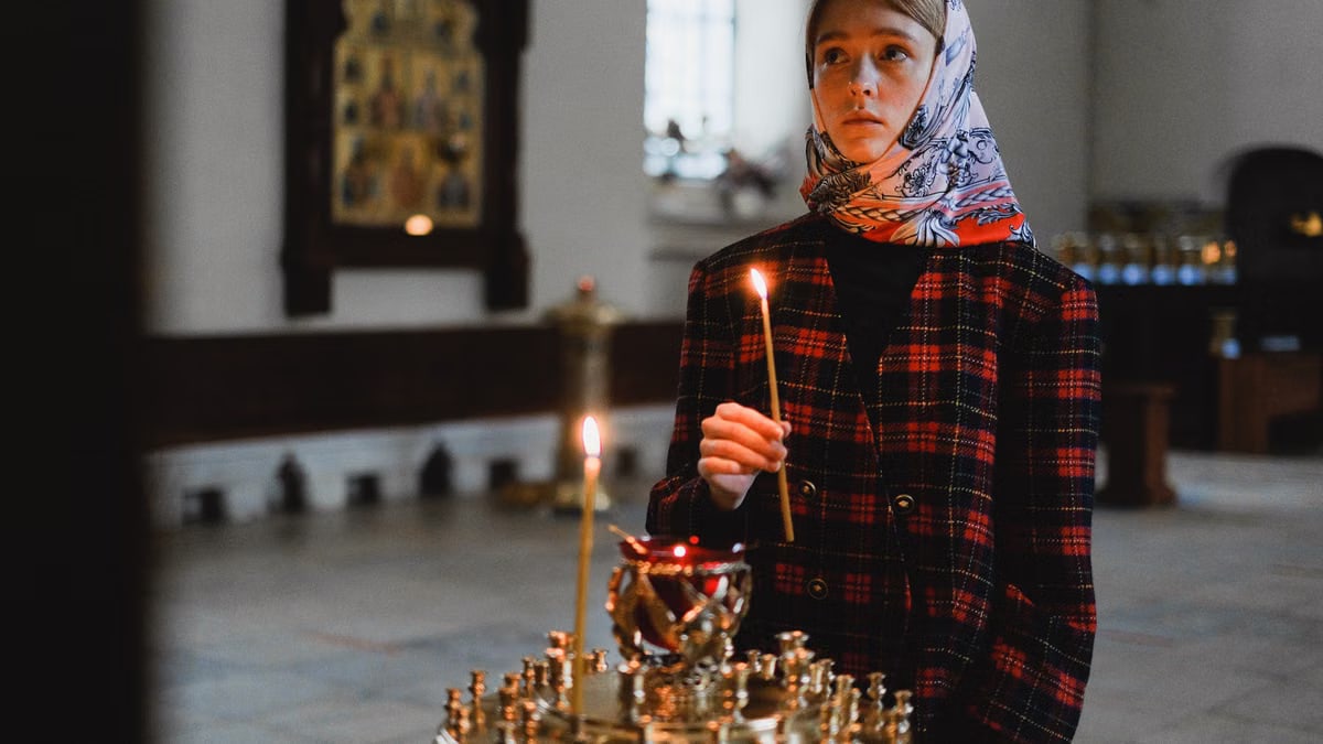 Teenager holding a candle in an Orthodox church, exemplifying spirituality and introspection.