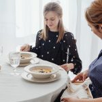 A serene scene of a mother and daughter dining together in a bright, cozy setting.
